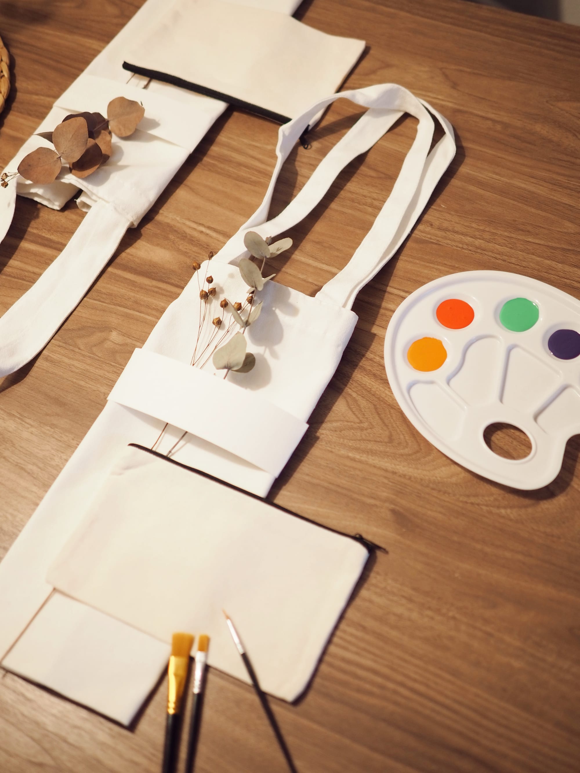Overhead view of tote bags, brushes and a palette on a wooden table