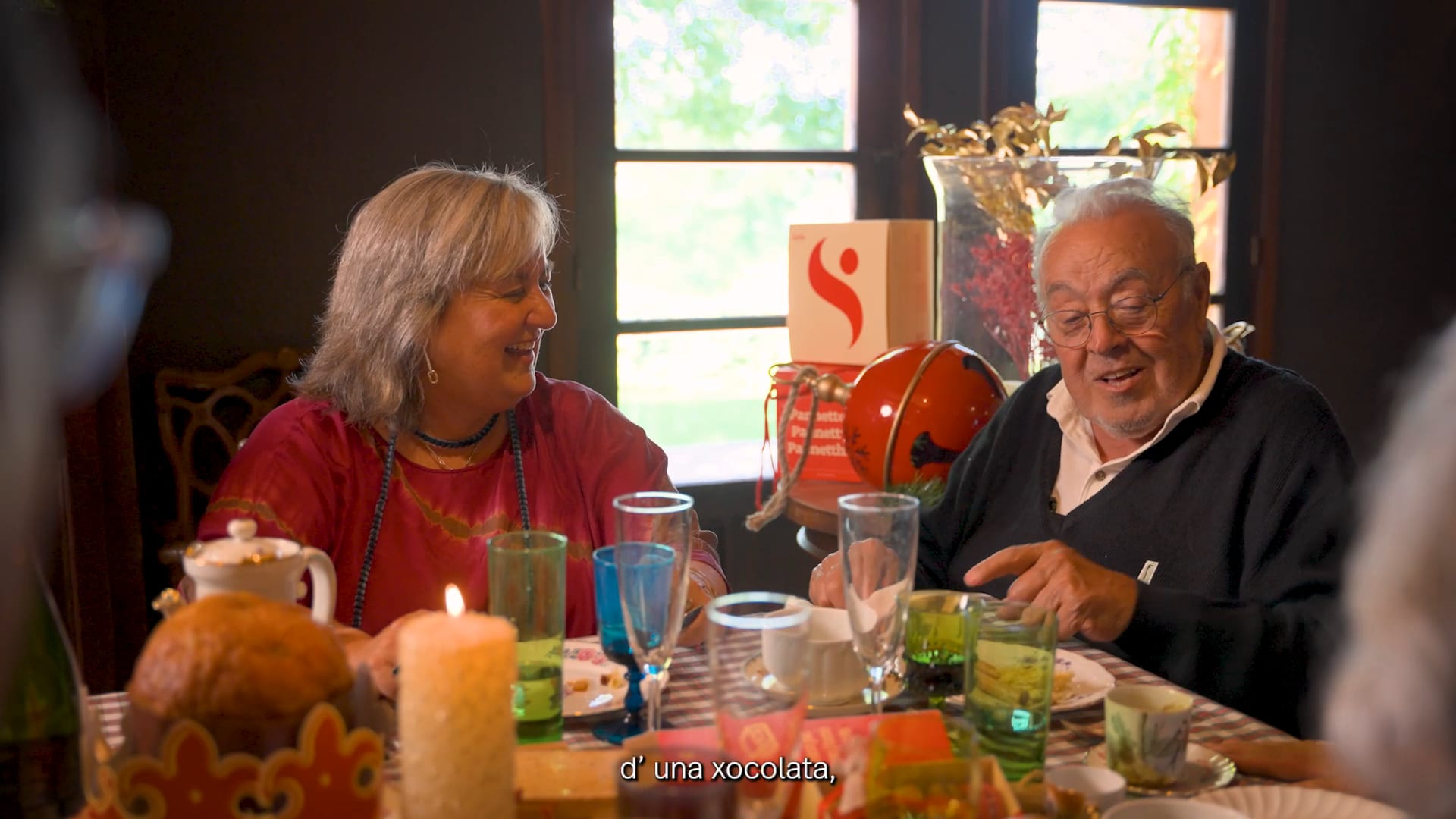 Family gathered around a Christmas dinner table in warm interior light, raising glasses