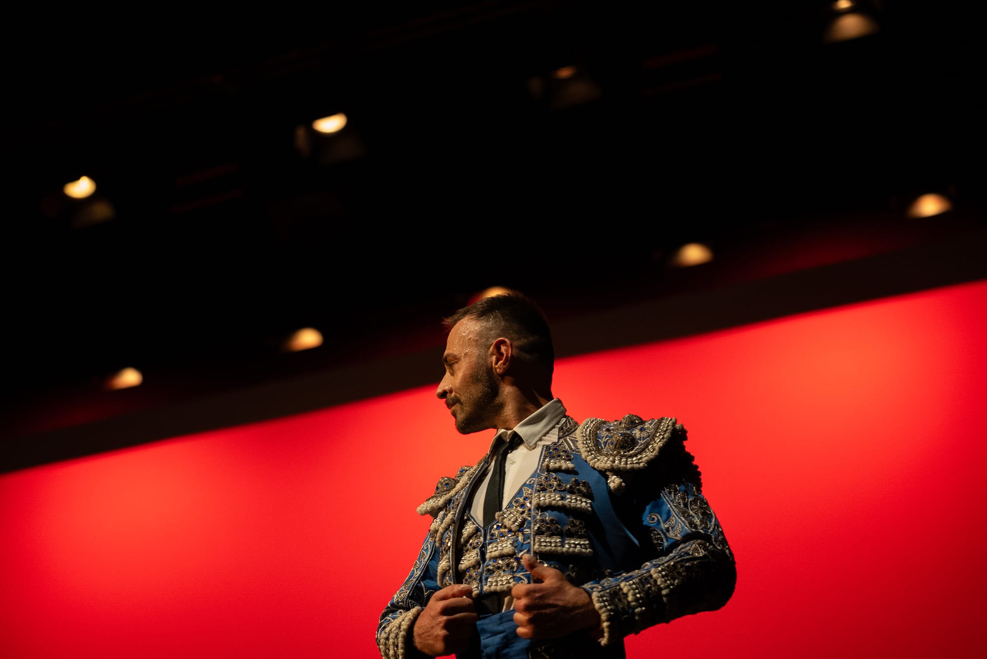 A bullfighter in profile silhouetted against a band of red light