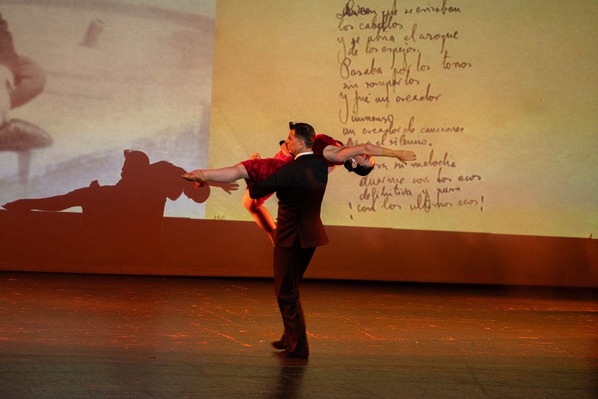 A couple dancing in front of a Lorca manuscript projected full-screen